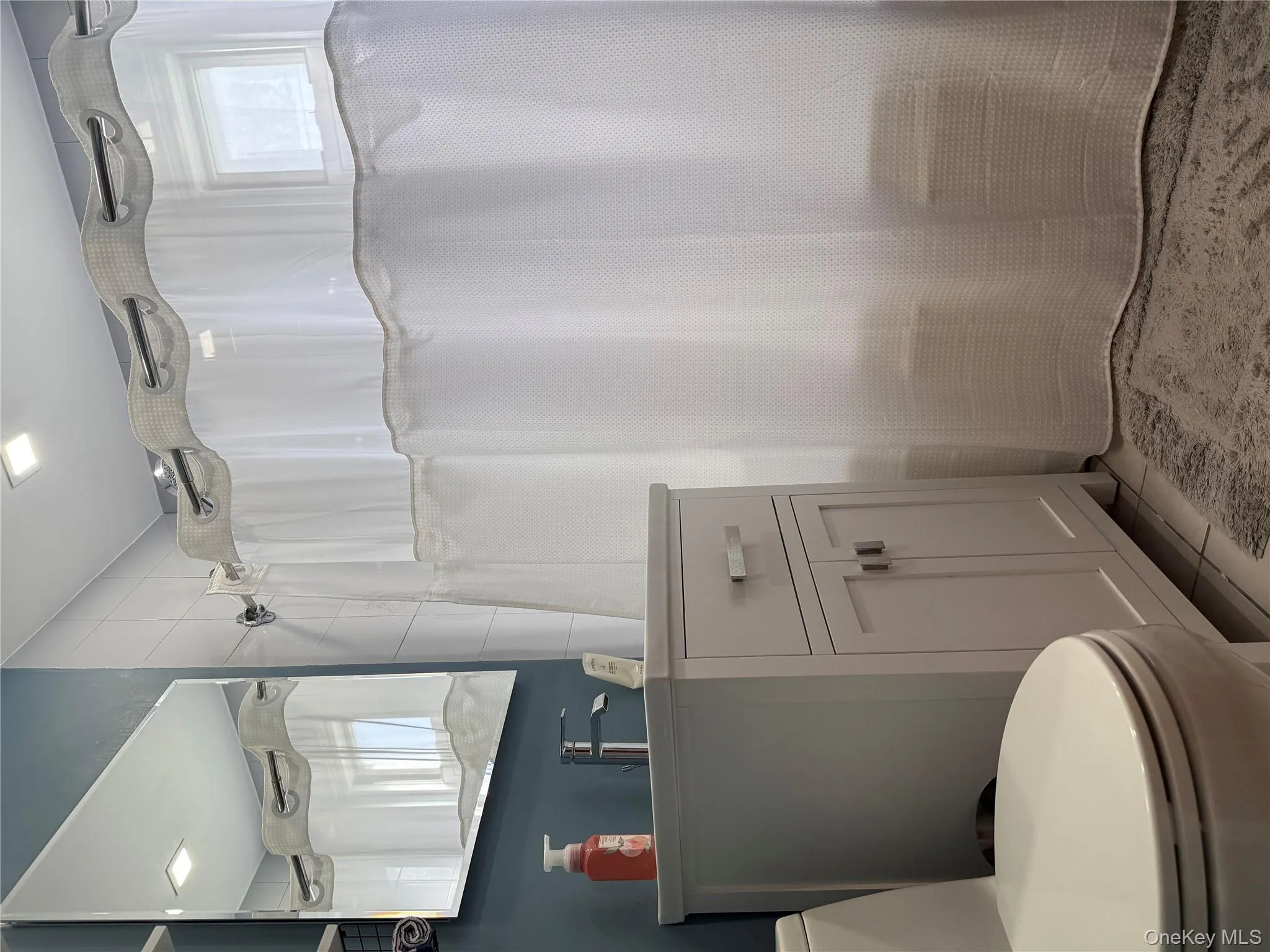 Bathroom featuring vanity, shower / bath combo with shower curtain, and light tile patterned floors Bathroom featuring vanity, shower / bath combo with shower curtain, and light tile patterned floors