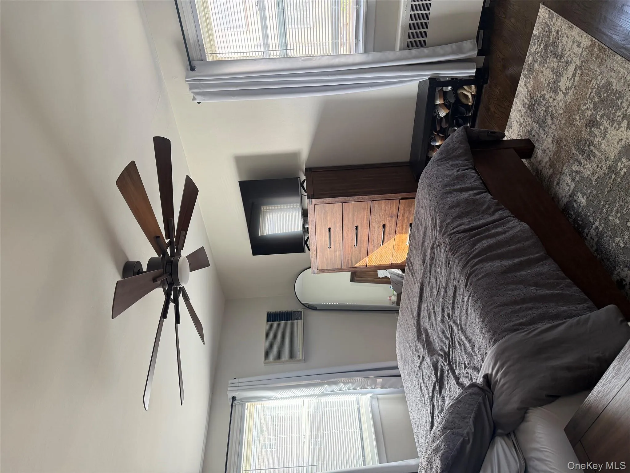 Bedroom with multiple windows, wood finished floors, radiator, and ceiling fan Bedroom with multiple windows, wood finished floors, radiator, and ceiling fan