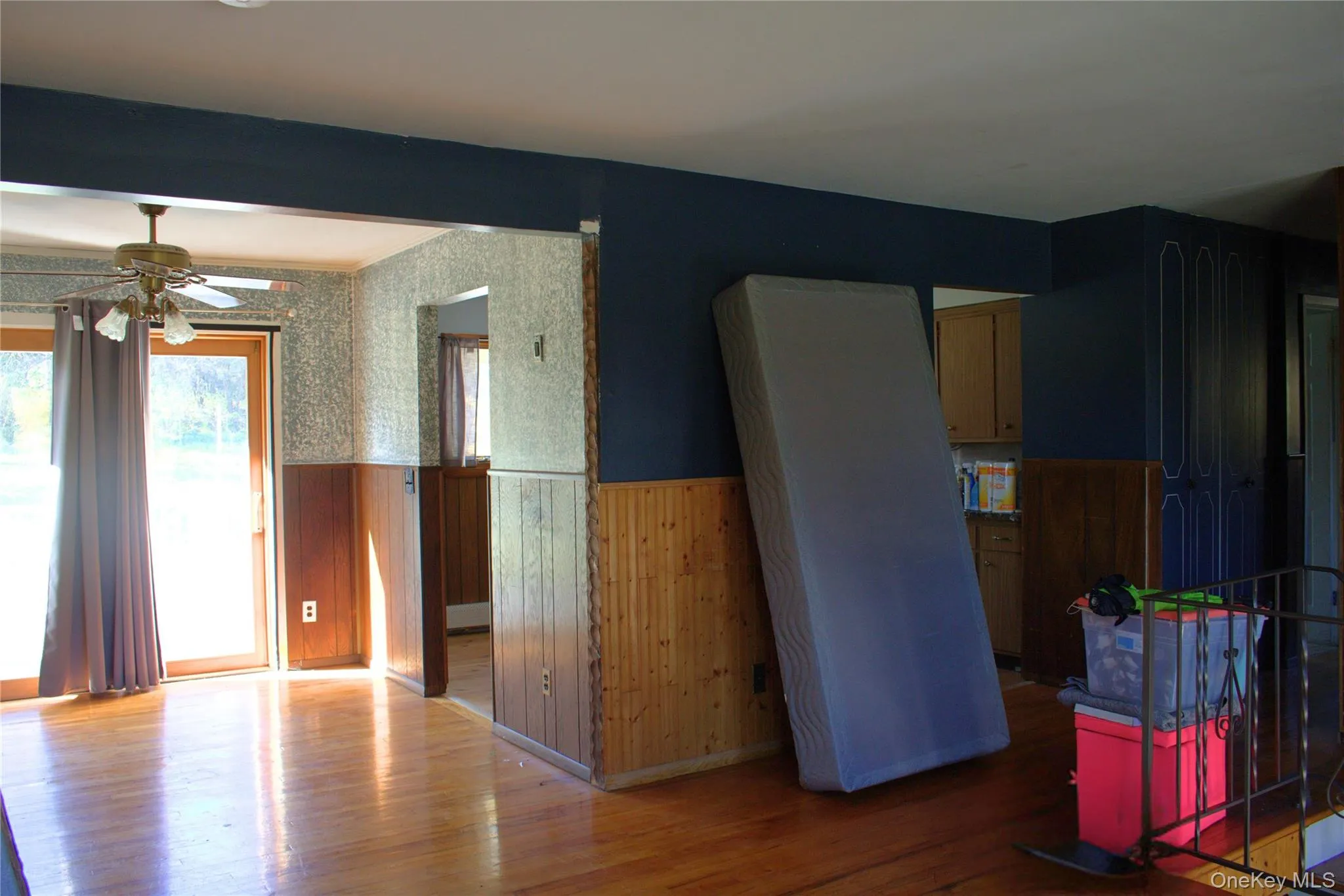 Kitchen featuring wainscoting, wooden walls, hardwood / wood-style flooring, wallpapered walls, and a ceiling fan Kitchen featuring wainscoting, wooden walls, hardwood / wood-style flooring, wallpapered walls, and a ceiling fan