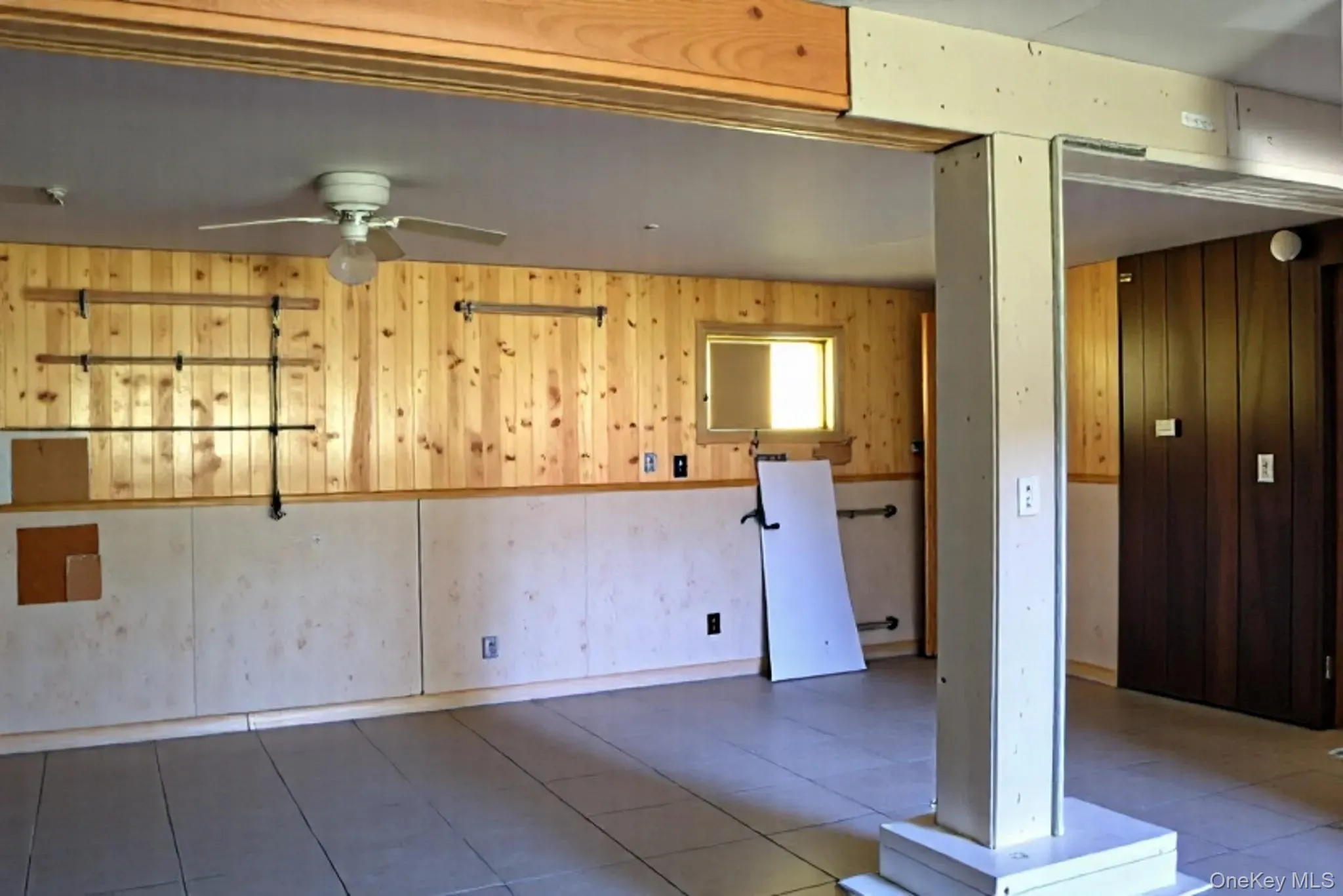 Spare room featuring wood walls, a ceiling fan, and tile patterned floors Spare room featuring wood walls, a ceiling fan, and tile patterned floors