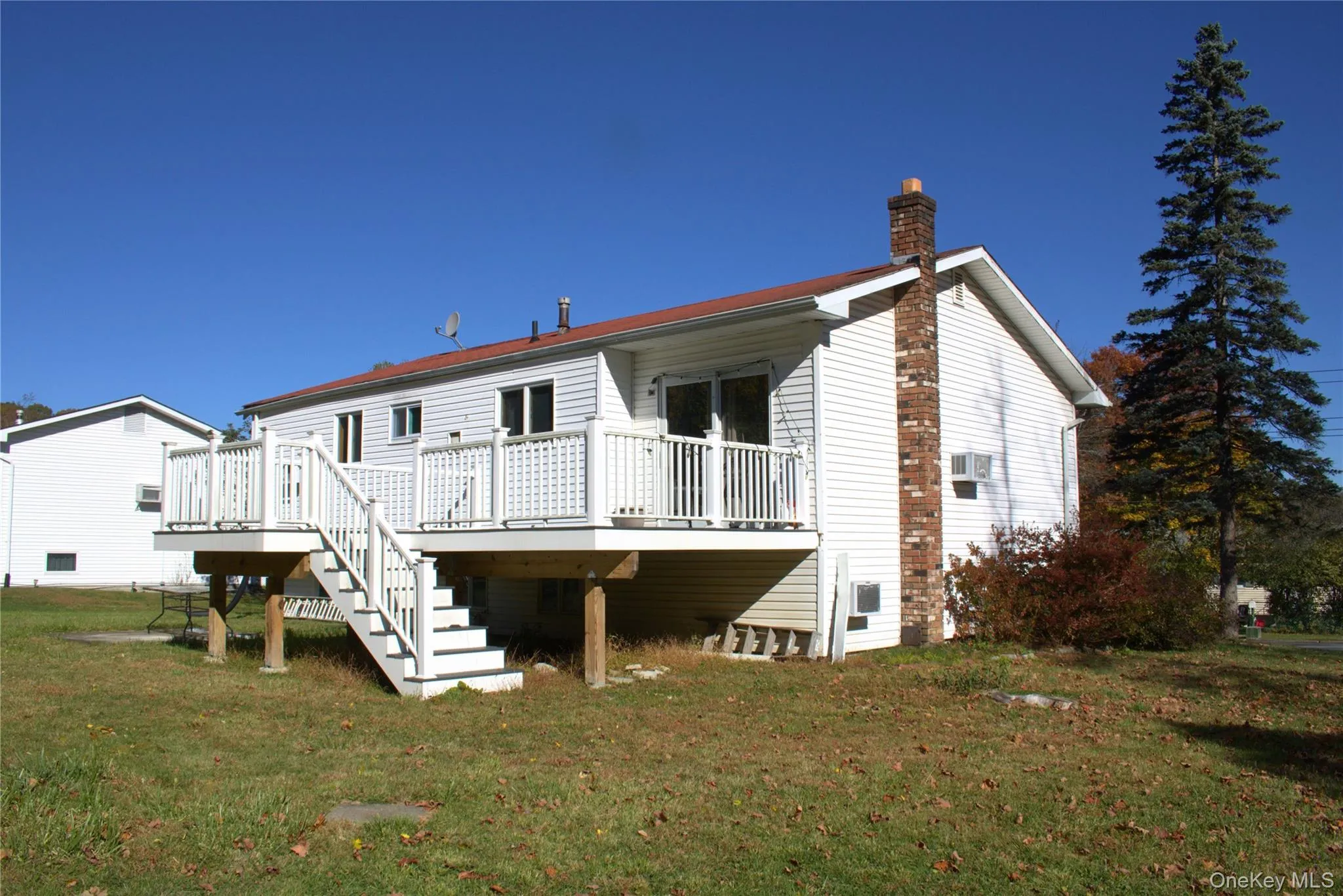 Rear view of house featuring a yard, a chimney, a deck, and stairs Rear view of house featuring a yard, a chimney, a deck, and stairs
