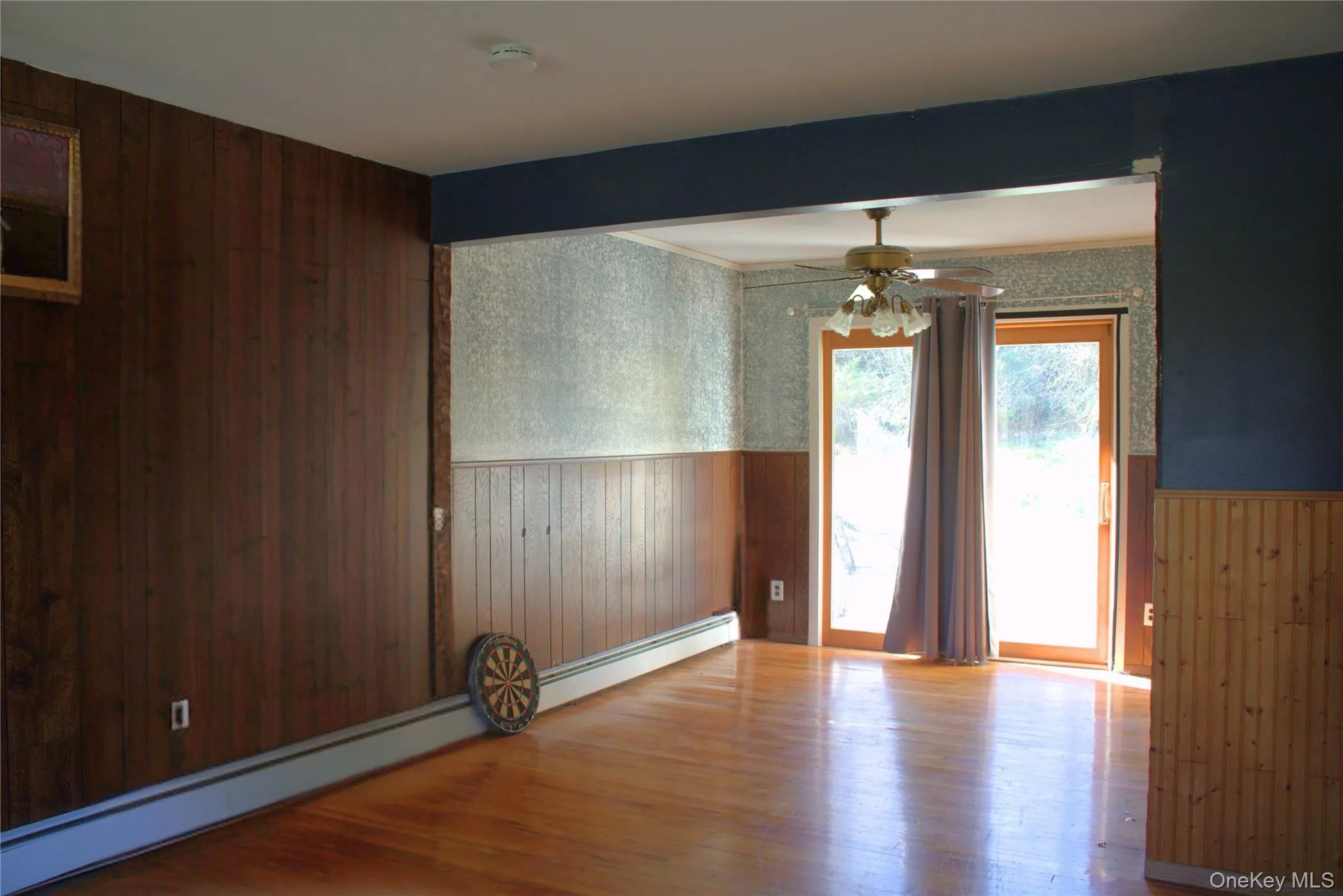 Spare room with wood walls, wood finished floors, a wainscoted wall, a baseboard heating unit, and wallpapered walls Spare room with wood walls, wood finished floors, a wainscoted wall, a baseboard heating unit, and wallpapered walls
