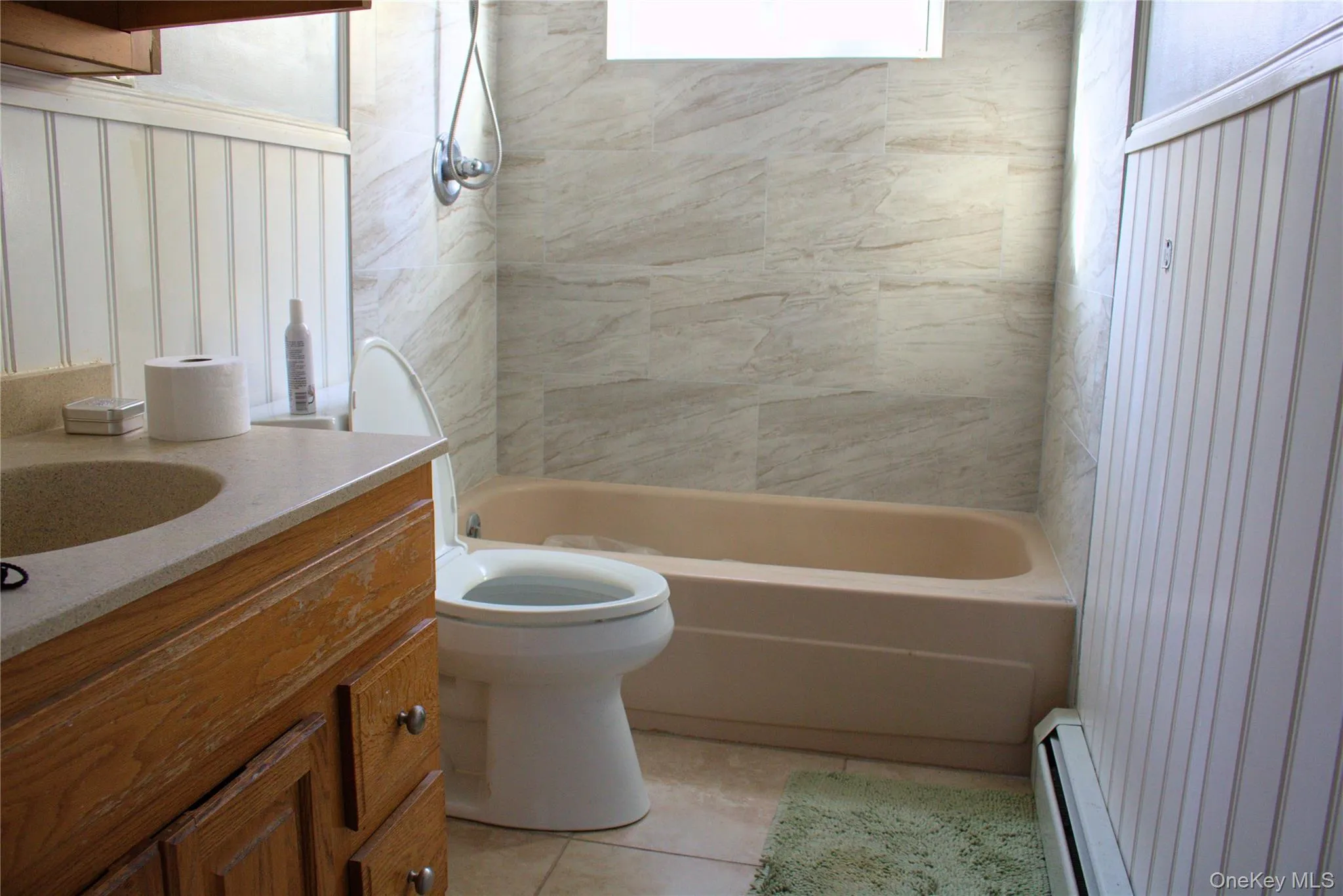 Bathroom featuring vanity, a baseboard radiator, light tile patterned floors, and  shower combination Bathroom featuring vanity, a baseboard radiator, light tile patterned floors, and  shower combination