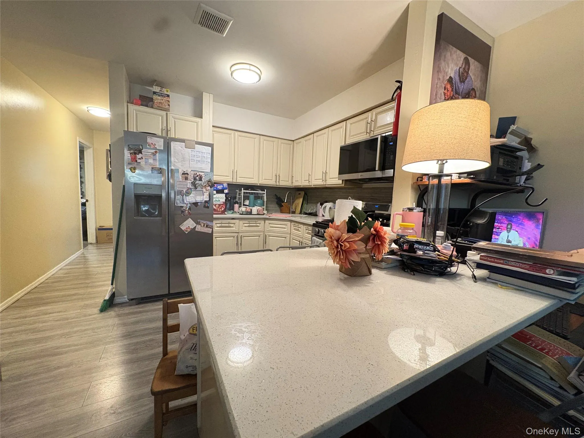 Kitchen with a kitchen bar, a peninsula, stainless steel appliances, dark wood-style flooring, and light stone counters Kitchen with a kitchen bar, a peninsula, stainless steel appliances, dark wood-style flooring, and light stone counters
