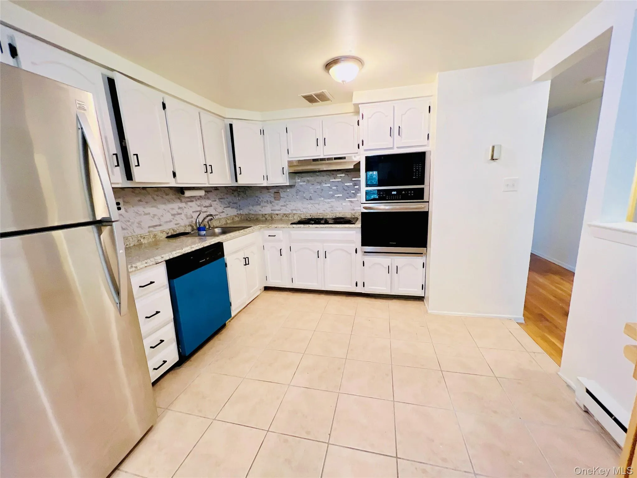 Kitchen featuring appliances with stainless steel finishes, tasteful backsplash, light tile patterned flooring, and white cabinets Kitchen featuring appliances with stainless steel finishes, tasteful backsplash, light tile patterned flooring, and white cabinets
