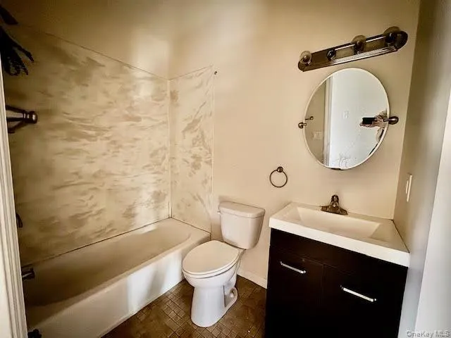 Bathroom with vanity, shower / tub combination, and dark tile patterned floors Bathroom with vanity, shower / tub combination, and dark tile patterned floors