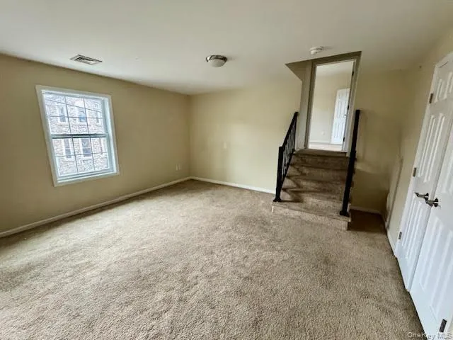 Unfurnished living room with light colored carpet and stairway into the bedroom... Unfurnished living room with light colored carpet and stairway into the bedroom...