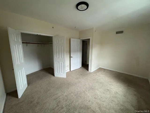 Unfurnished bedroom featuring carpet flooring a closet and ceiling light. Unfurnished bedroom featuring carpet flooring a closet and ceiling light.