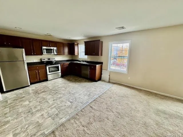 Kitchen featuring stainless steel appliances, dark countertops, and dark brown cabinets Kitchen featuring stainless steel appliances, dark countertops, and dark brown cabinets