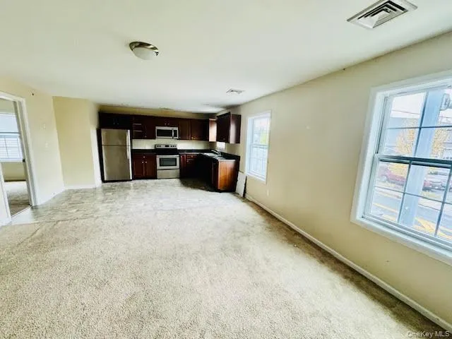 Kitchen featuring appliances with stainless steel finishes, dark brown cabinets, light brown carpet, open floor plan. Kitchen featuring appliances with stainless steel finishes, dark brown cabinets, light brown carpet, open floor plan.