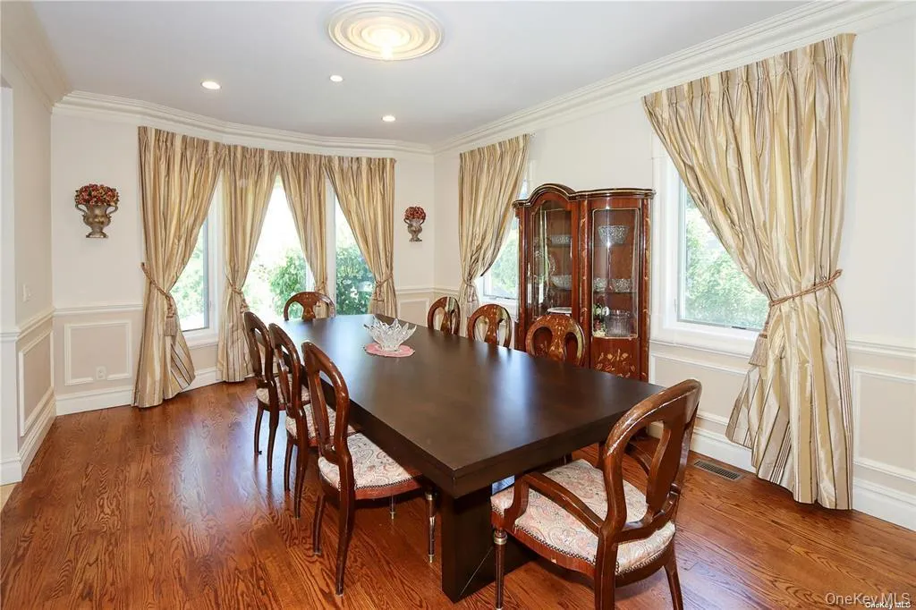 Dining area with plenty of natural light, a decorative wall, a wainscoted wall, wood finished floors, and crown molding Dining area with plenty of natural light, a decorative wall, a wainscoted wall, wood finished floors, and crown molding