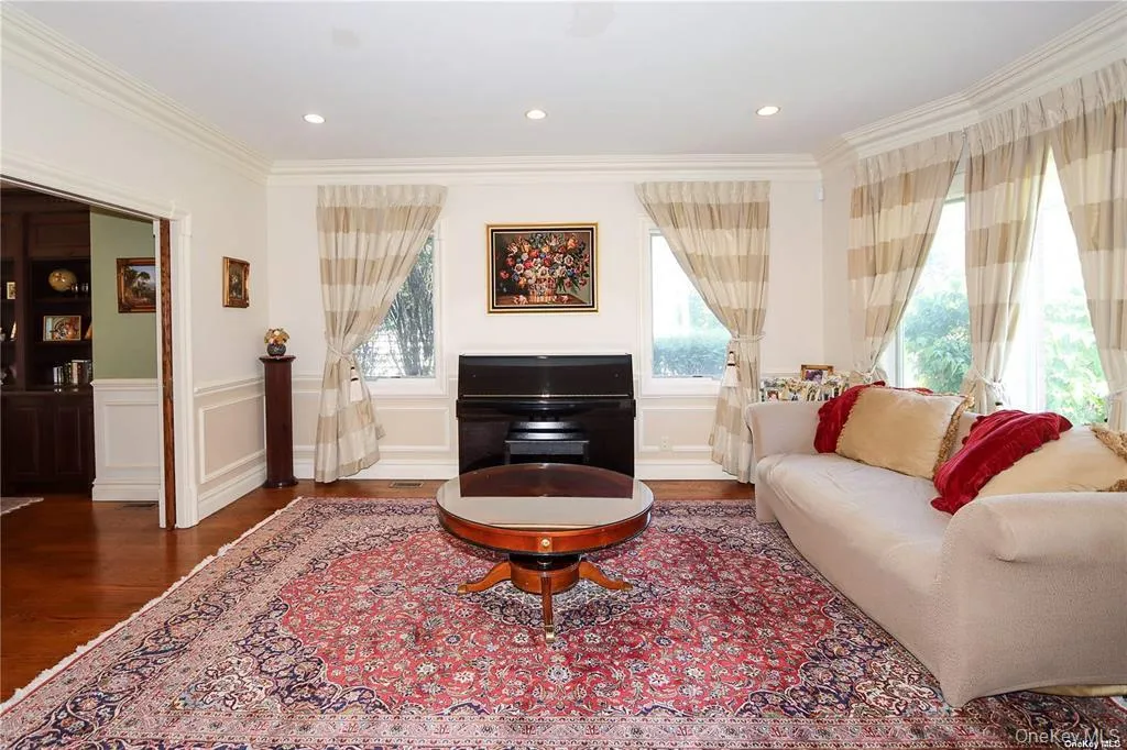 Living area featuring wood finished floors, healthy amount of natural light, crown molding, wainscoting, and recessed lighting Living area featuring wood finished floors, healthy amount of natural light, crown molding, wainscoting, and recessed lighting