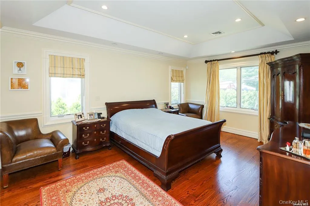 Bedroom with a tray ceiling, multiple windows, ornamental molding, wood finished floors, and recessed lighting Bedroom with a tray ceiling, multiple windows, ornamental molding, wood finished floors, and recessed lighting