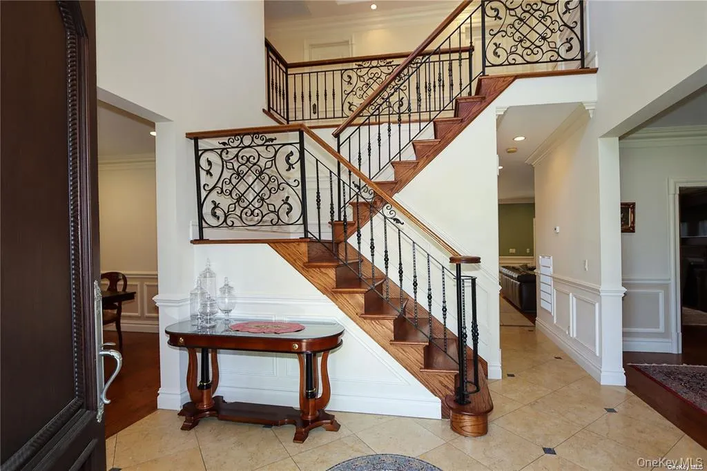 Stairway with ornamental molding, tile patterned floors, a towering ceiling, and a decorative wall Stairway with ornamental molding, tile patterned floors, a towering ceiling, and a decorative wall