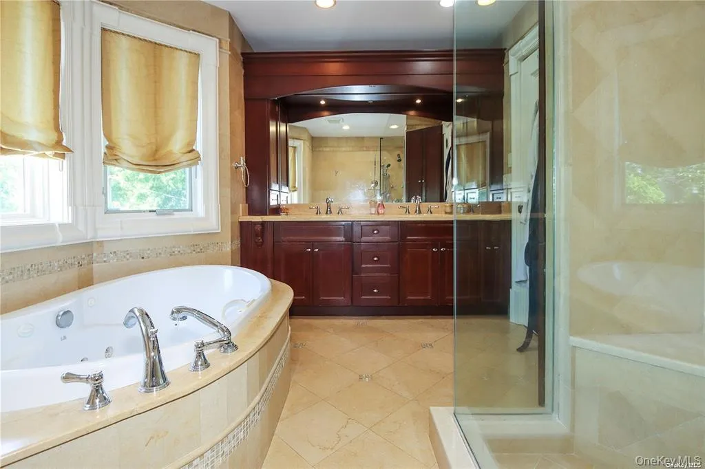 Full bath featuring double vanity, a whirlpool tub, a shower stall, and light tile patterned floors Full bath featuring double vanity, a whirlpool tub, a shower stall, and light tile patterned floors