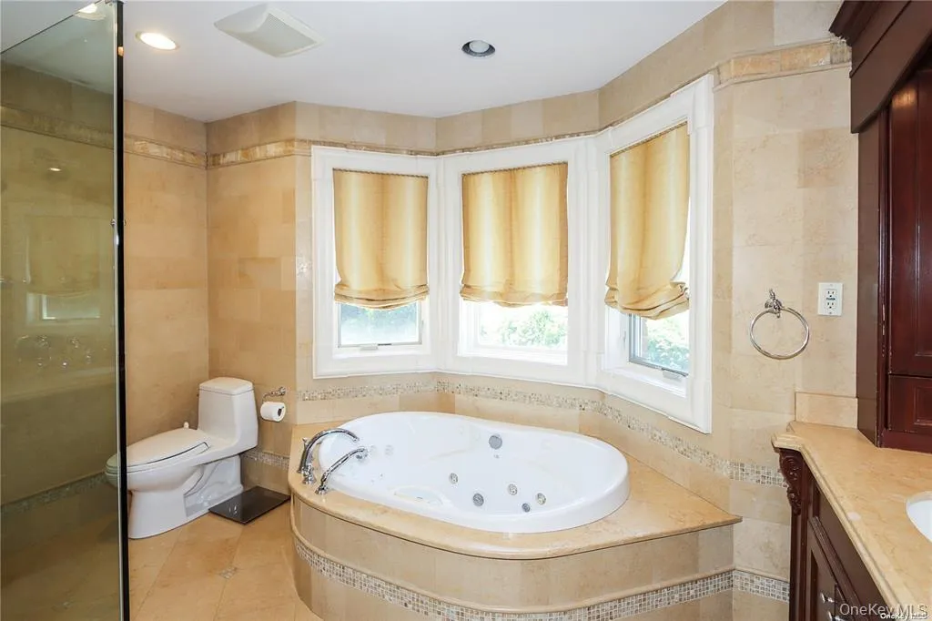Bathroom featuring tile walls, vanity, tile patterned floors, a stall shower, and a jetted tub Bathroom featuring tile walls, vanity, tile patterned floors, a stall shower, and a jetted tub