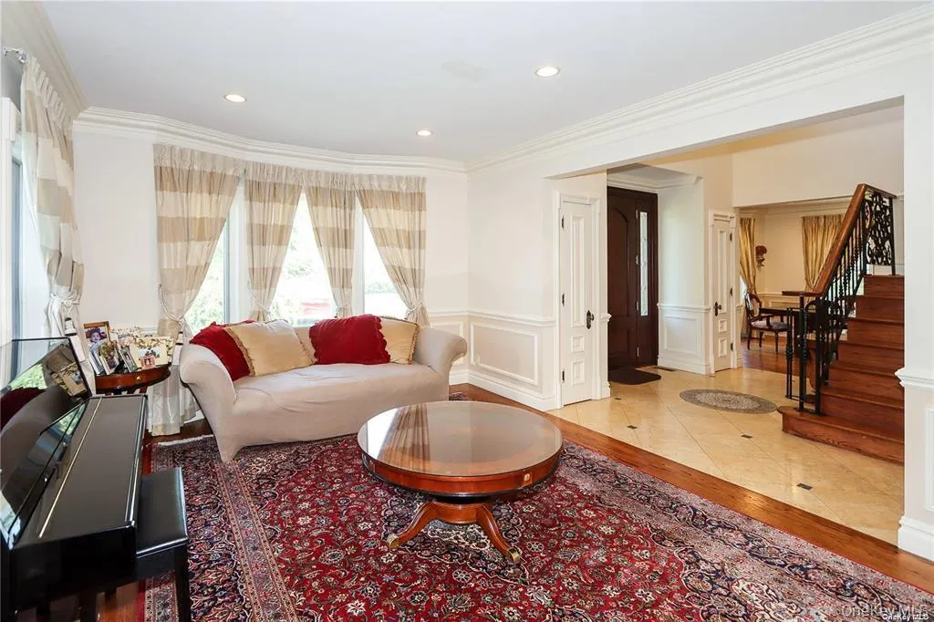 Living area featuring light wood-style flooring, ornamental molding, a wainscoted wall, recessed lighting, and a decorative wall Living area featuring light wood-style flooring, ornamental molding, a wainscoted wall, recessed lighting, and a decorative wall