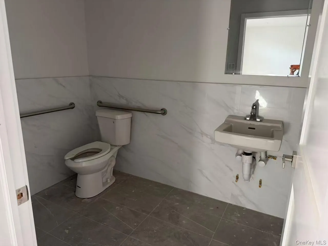 Half bath with tile walls, dark tile patterned flooring, and wainscoting Half bath with tile walls, dark tile patterned flooring, and wainscoting