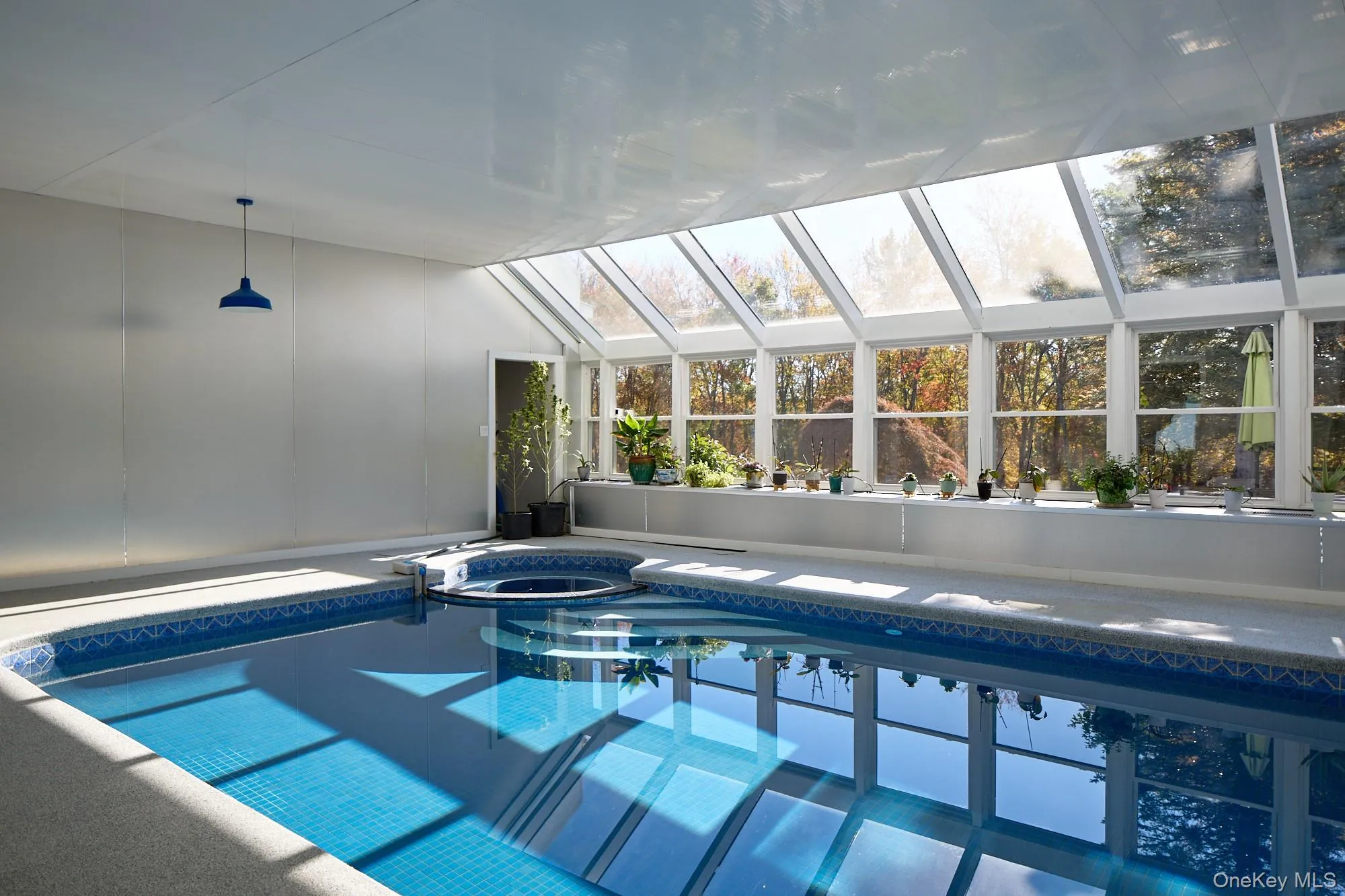 View of pool featuring a pool with connected hot tub, a skylight, and a sunroom View of pool featuring a pool with connected hot tub, a skylight, and a sunroom