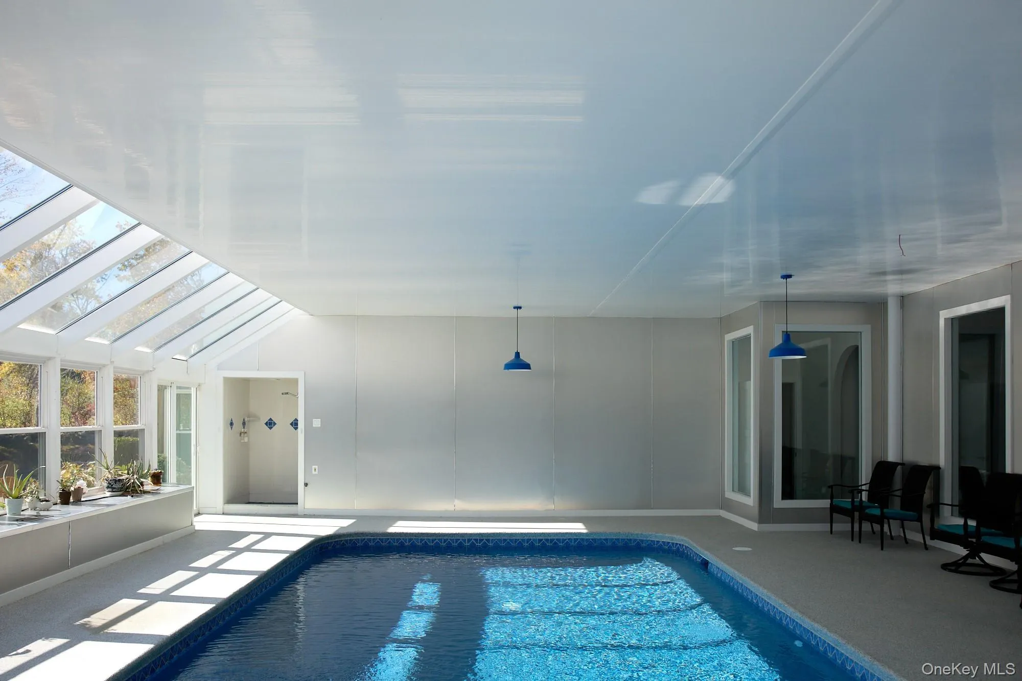 Indoor pool featuring a skylight and a sunroom Indoor pool featuring a skylight and a sunroom