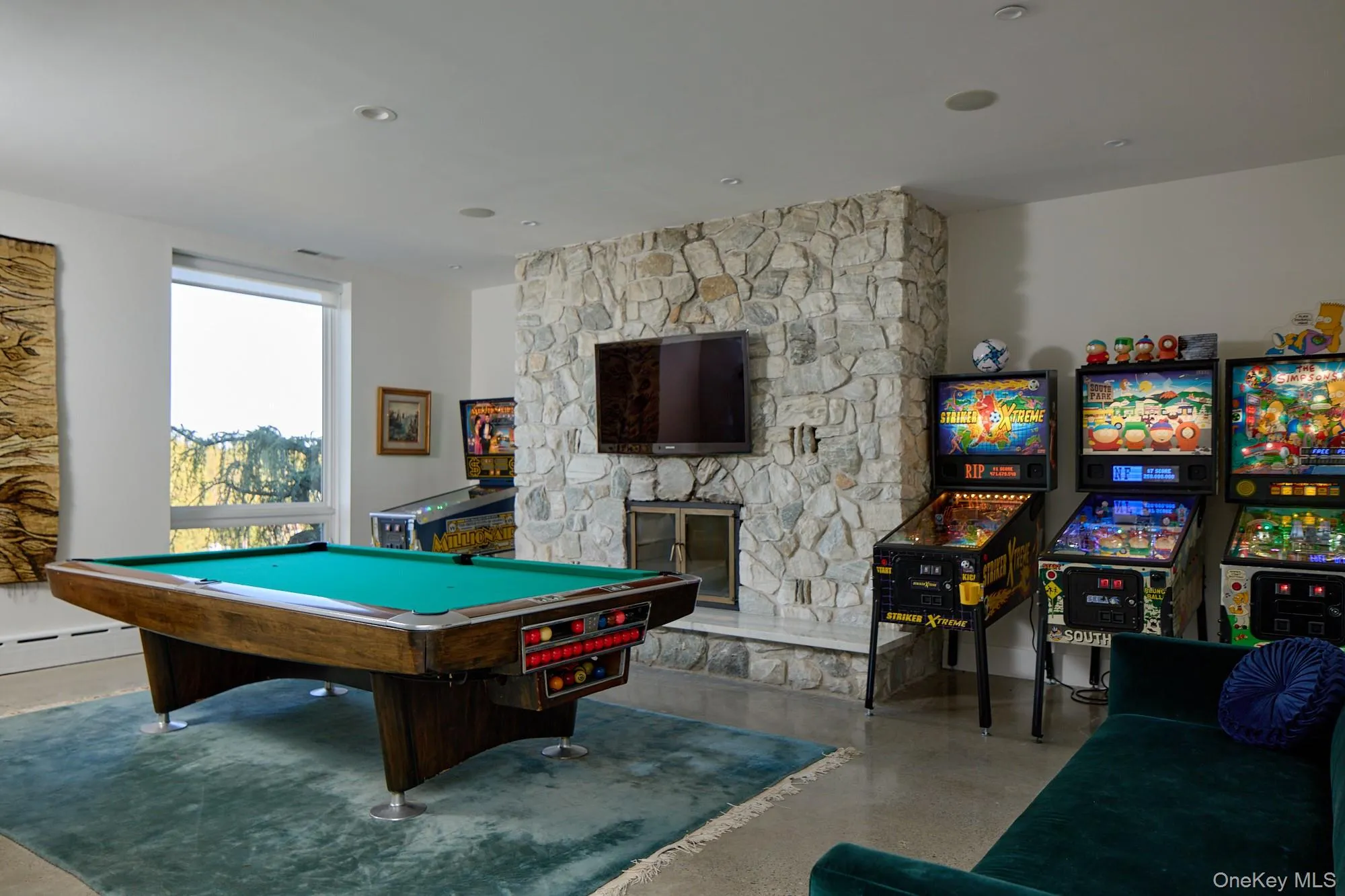 Rec room featuring a stone fireplace, billiards, recessed lighting, and a baseboard heating unit Rec room featuring a stone fireplace, billiards, recessed lighting, and a baseboard heating unit