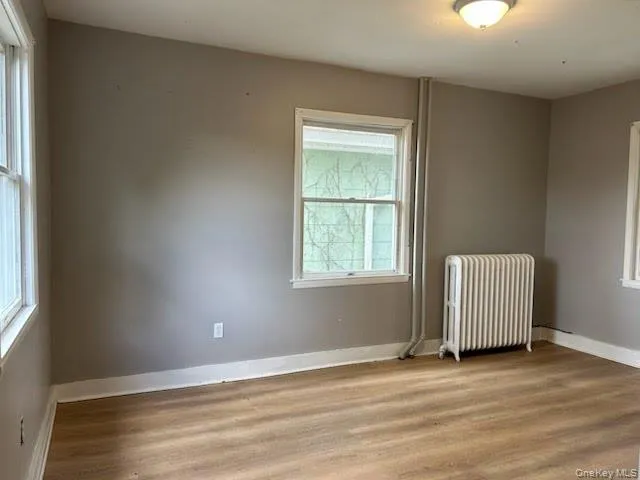 Spare room featuring radiator heating unit and light wood-style floors Spare room featuring radiator heating unit and light wood-style floors