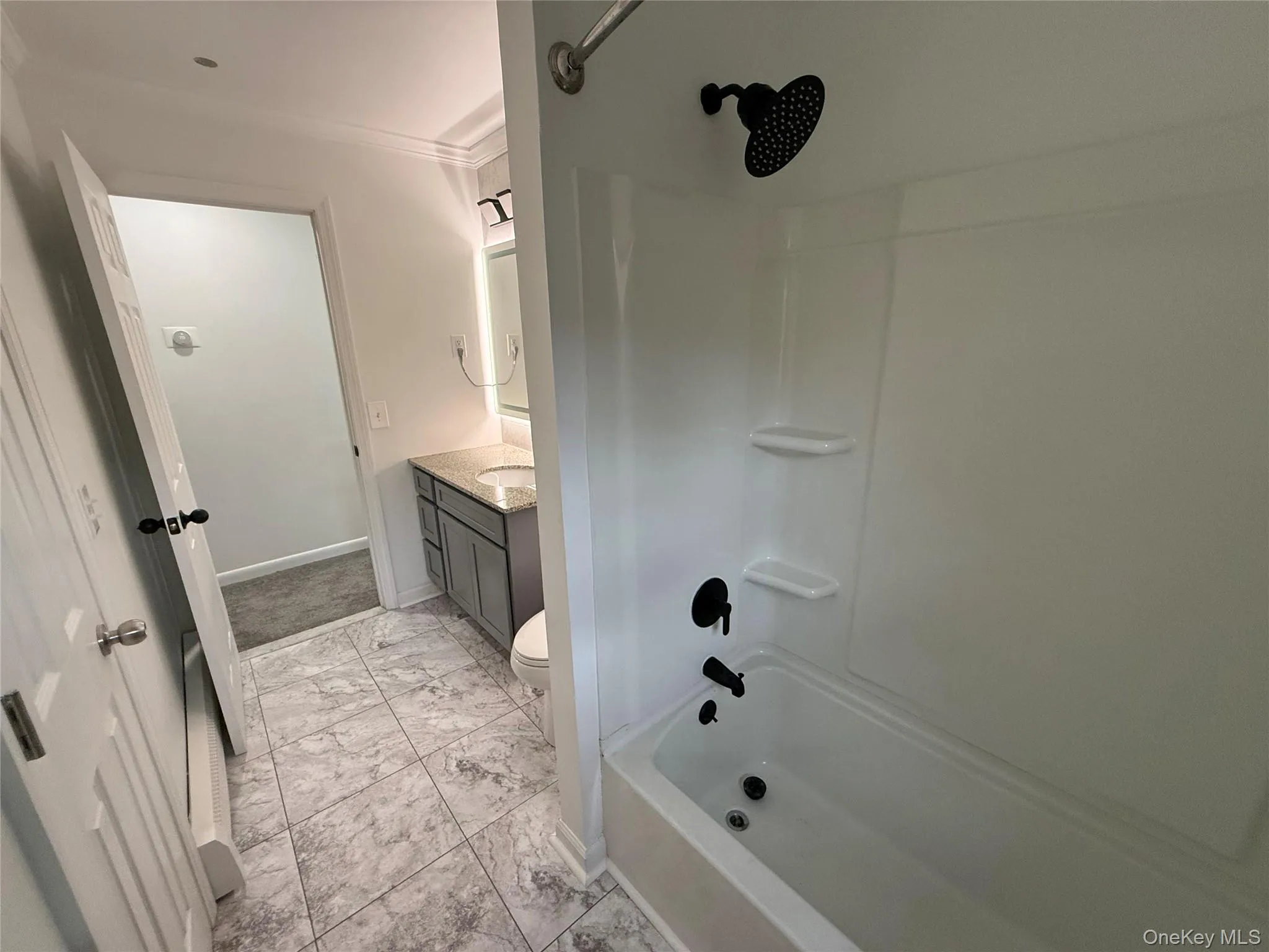 Full bathroom featuring vanity, washtub / shower combination, light marble finish flooring, and crown molding Full bathroom featuring vanity, washtub / shower combination, light marble finish flooring, and crown molding