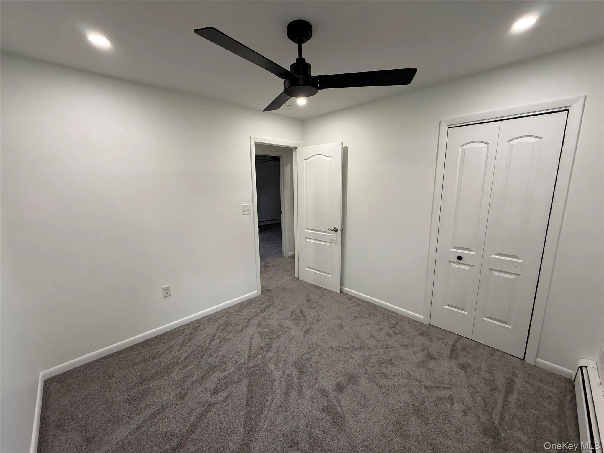 Unfurnished bedroom featuring a baseboard heating unit, dark carpet, recessed lighting, a ceiling fan, and a closet Unfurnished bedroom featuring a baseboard heating unit, dark carpet, recessed lighting, a ceiling fan, and a closet