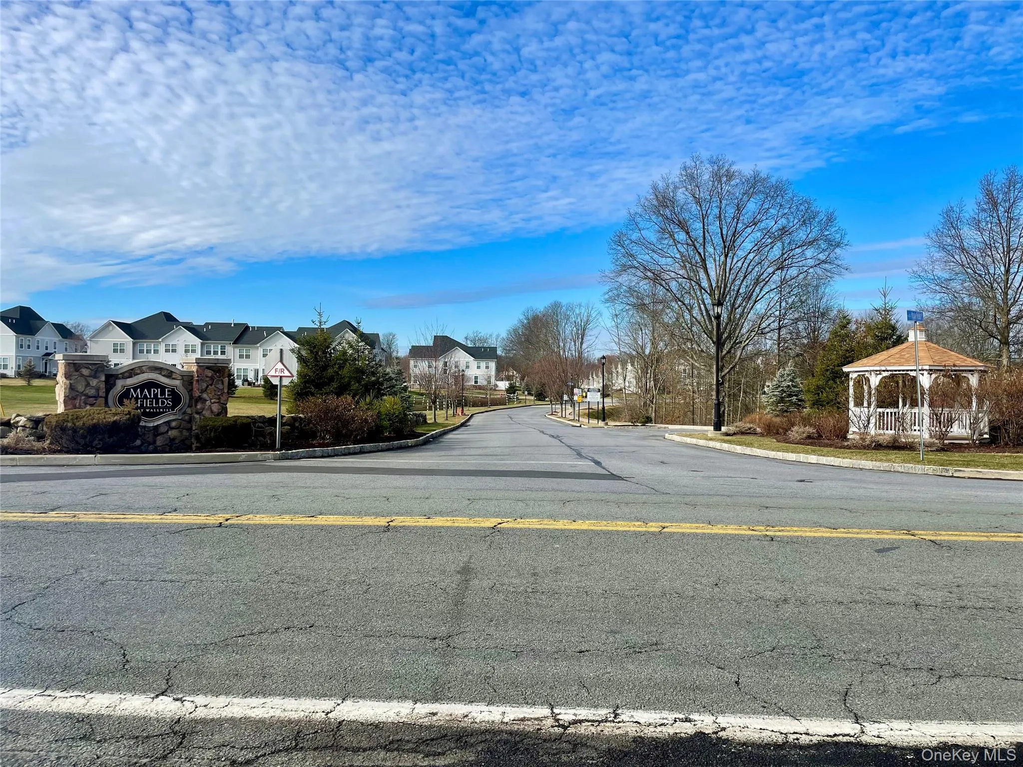View of asphalt street featuring curbs, a residential view, and traffic signs View of asphalt street featuring curbs, a residential view, and traffic signs
