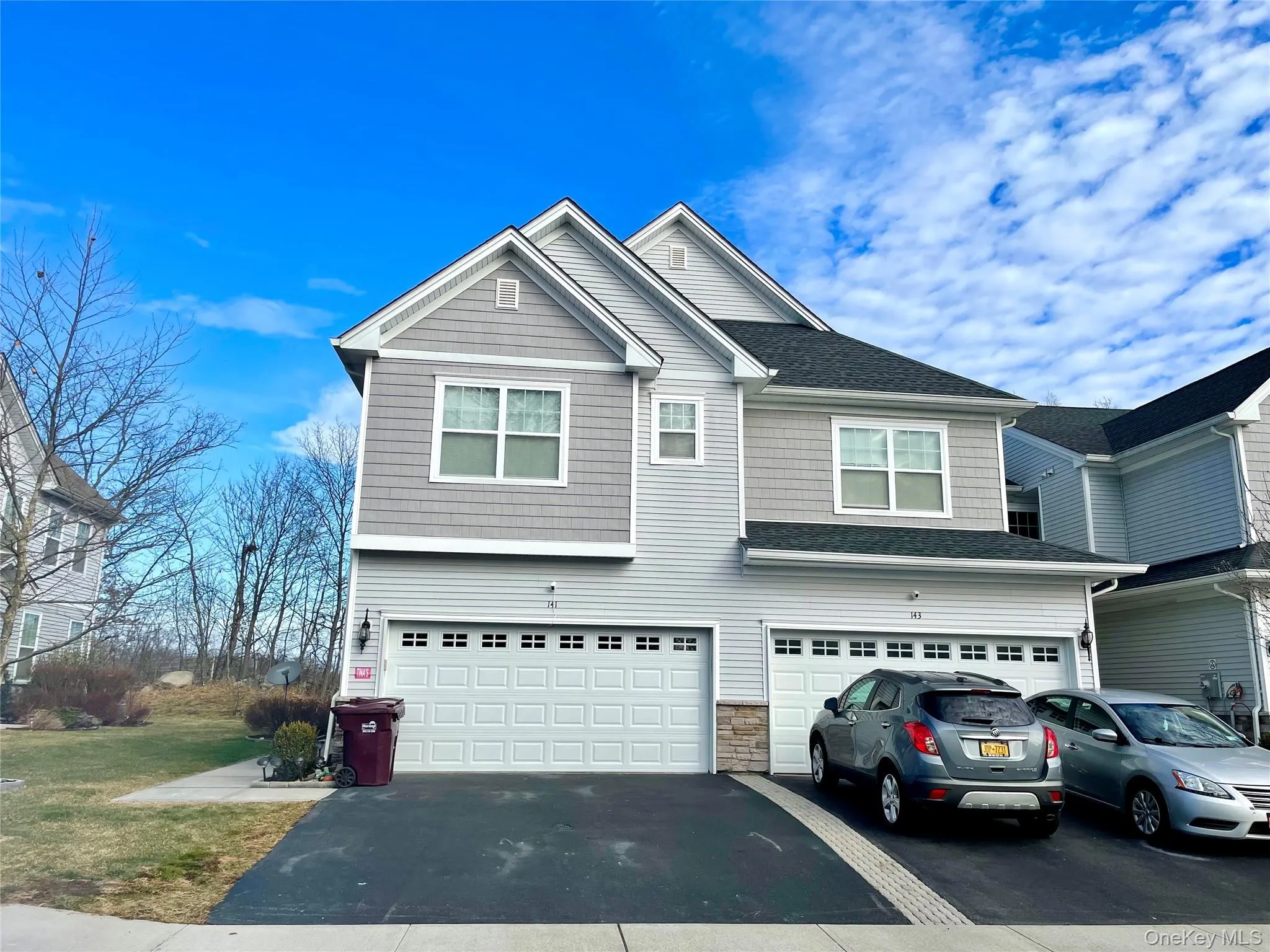 View of front of property featuring asphalt driveway, a garage, stone siding, and a shingled roof View of front of property featuring asphalt driveway, a garage, stone siding, and a shingled roof