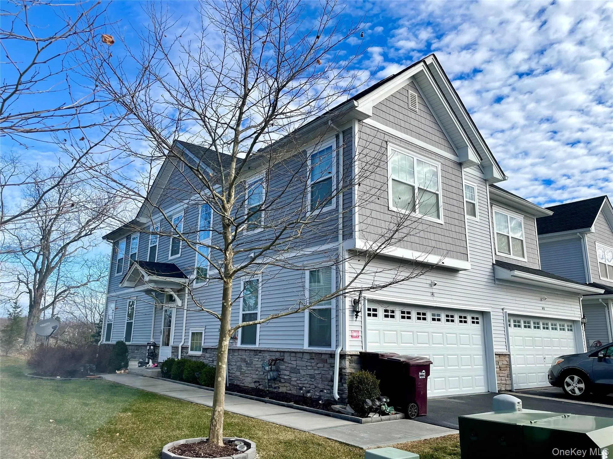 View of side of home featuring stone siding, an attached garage, driveway, and a lawn View of side of home featuring stone siding, an attached garage, driveway, and a lawn