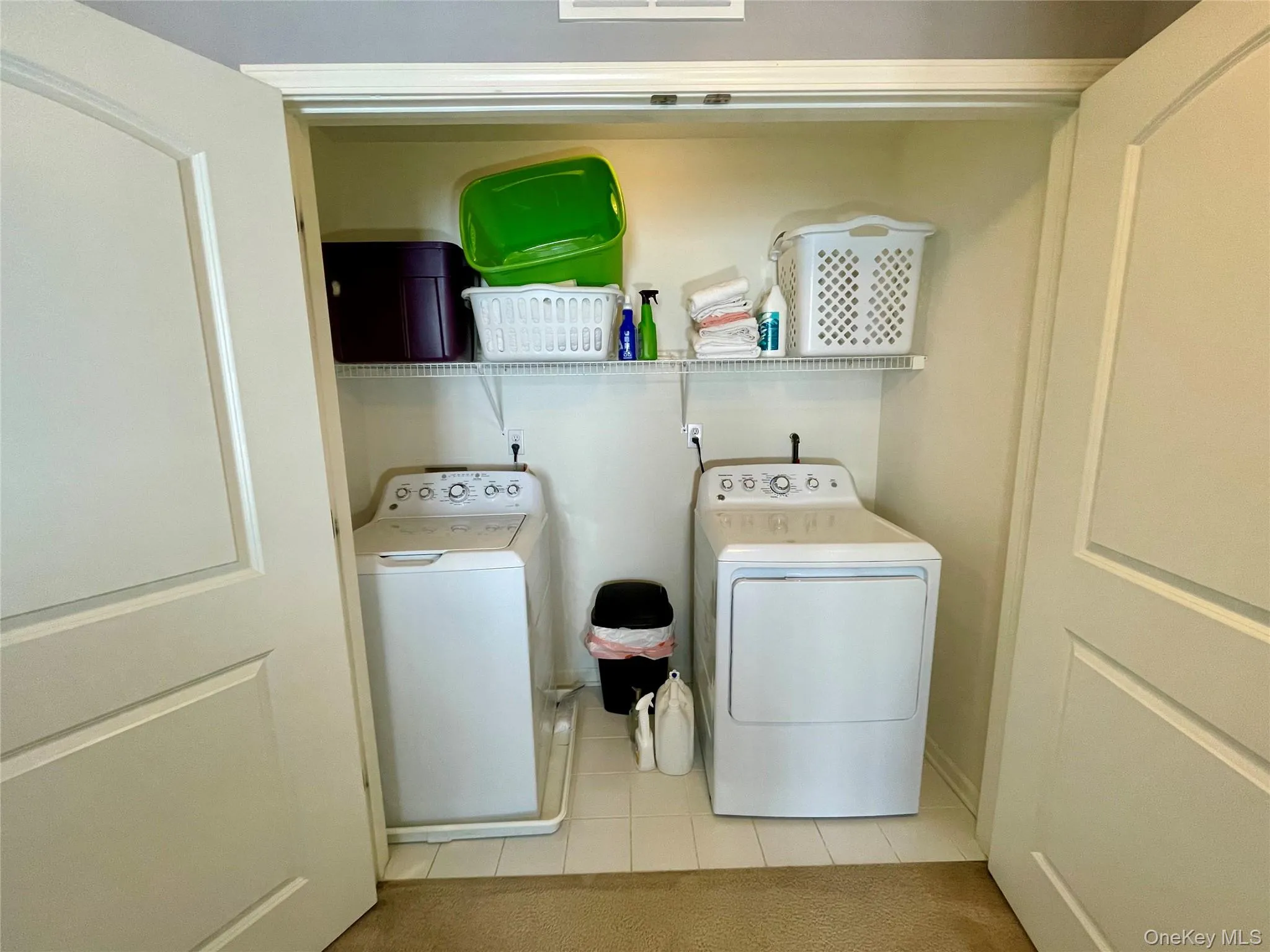 Laundry room with light tile patterned floors and separate washer and dryer Laundry room with light tile patterned floors and separate washer and dryer