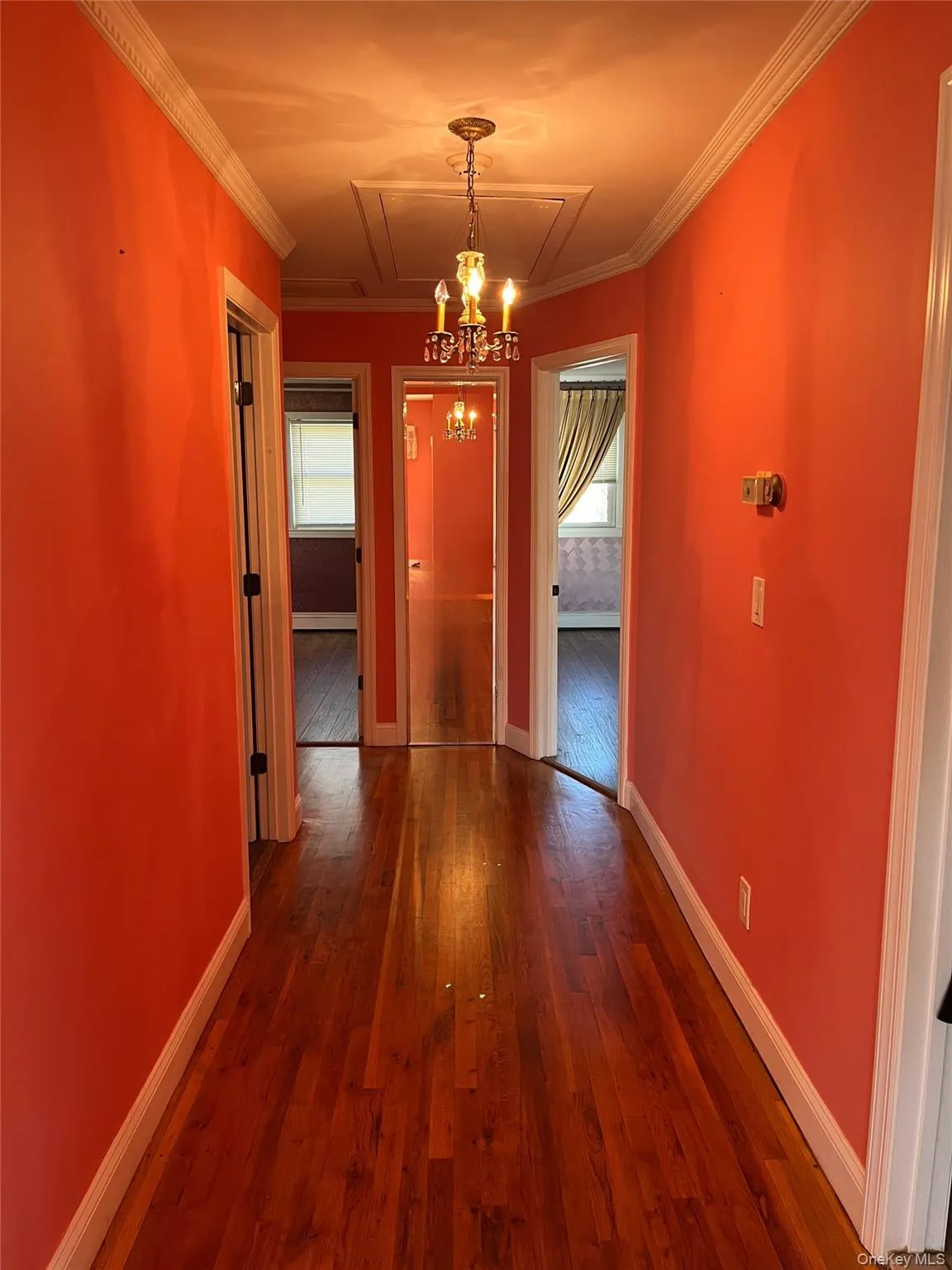 Unfurnished dining area with dark wood-style flooring, ornamental molding, and attic access Unfurnished dining area with dark wood-style flooring, ornamental molding, and attic access