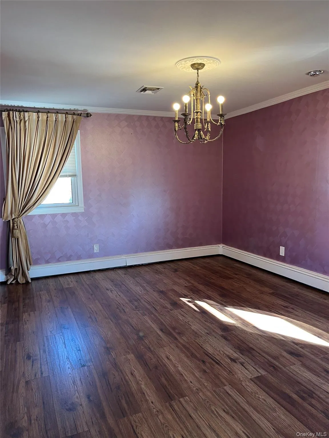 Unfurnished room featuring wallpapered walls, crown molding, dark wood-type flooring, a chandelier, and baseboard heating Unfurnished room featuring wallpapered walls, crown molding, dark wood-type flooring, a chandelier, and baseboard heating
