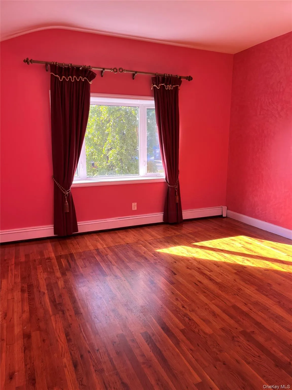 Spare room featuring wood finished floors and a baseboard heating unit Spare room featuring wood finished floors and a baseboard heating unit
