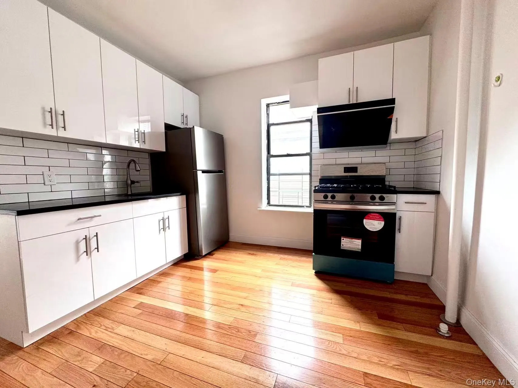 Kitchen featuring dark countertops, backsplash, stainless steel appliances, and white cabinets Kitchen featuring dark countertops, backsplash, stainless steel appliances, and white cabinets