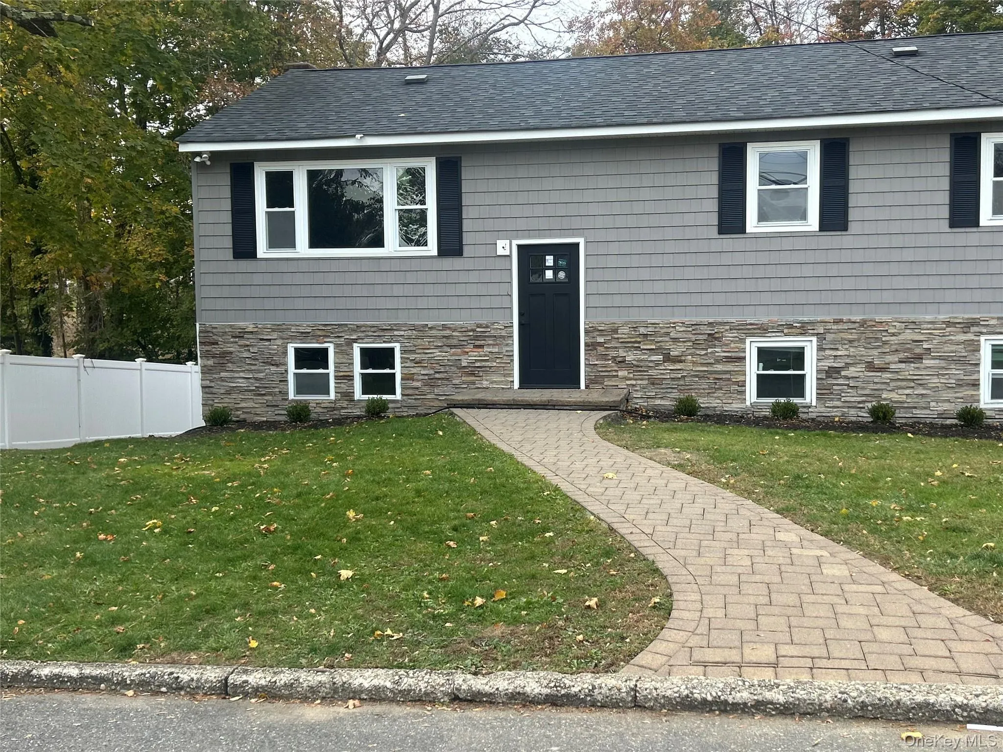 Split foyer home featuring stone siding and roof with shingles Split foyer home featuring stone siding and roof with shingles