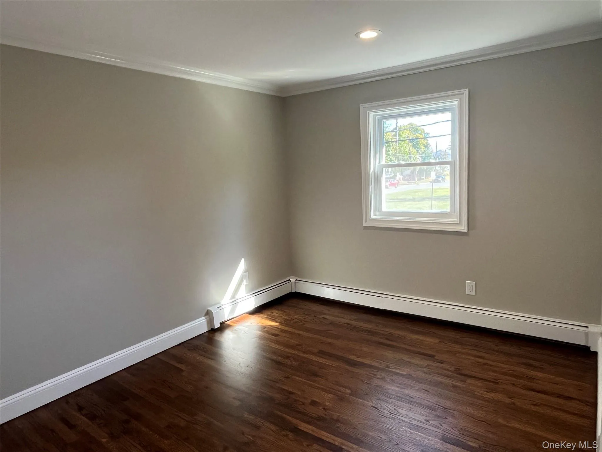Unfurnished room featuring ornamental molding, dark wood-style floors, baseboard heating, and recessed lighting Unfurnished room featuring ornamental molding, dark wood-style floors, baseboard heating, and recessed lighting