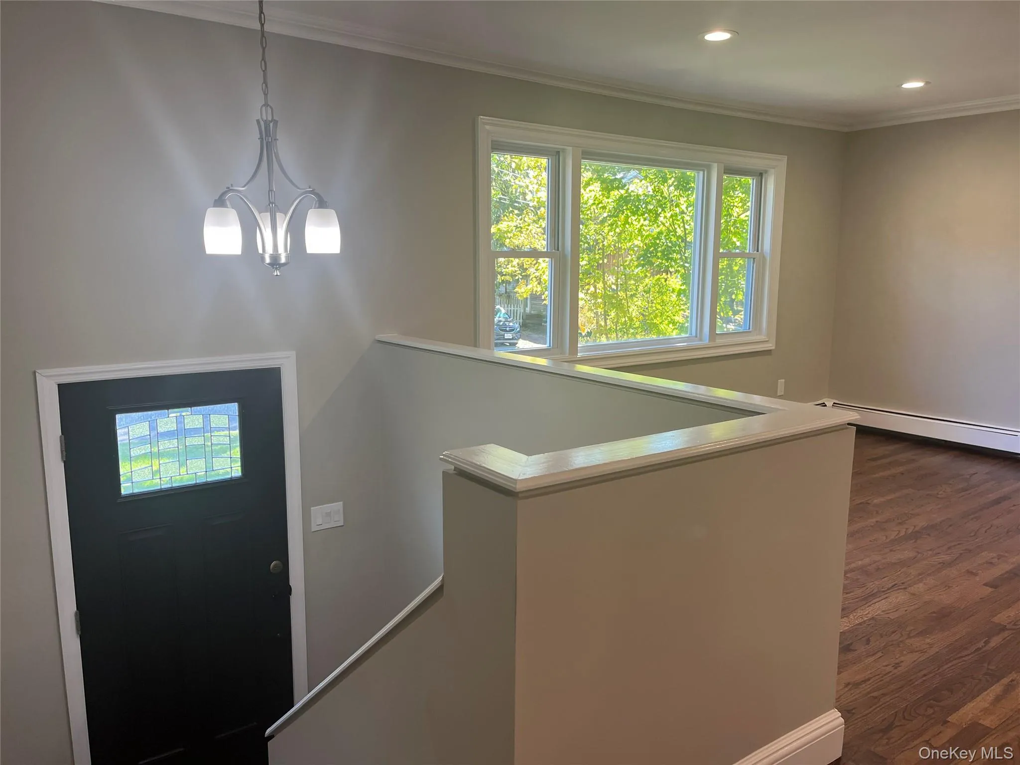 Entrance foyer with dark wood-style flooring, a chandelier, ornamental molding, and recessed lighting Entrance foyer with dark wood-style flooring, a chandelier, ornamental molding, and recessed lighting