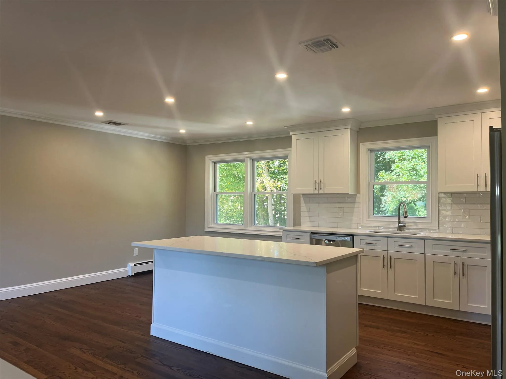 Kitchen with recessed lighting, crown molding, white cabinetry, backsplash, and dark wood-type flooring Kitchen with recessed lighting, crown molding, white cabinetry, backsplash, and dark wood-type flooring