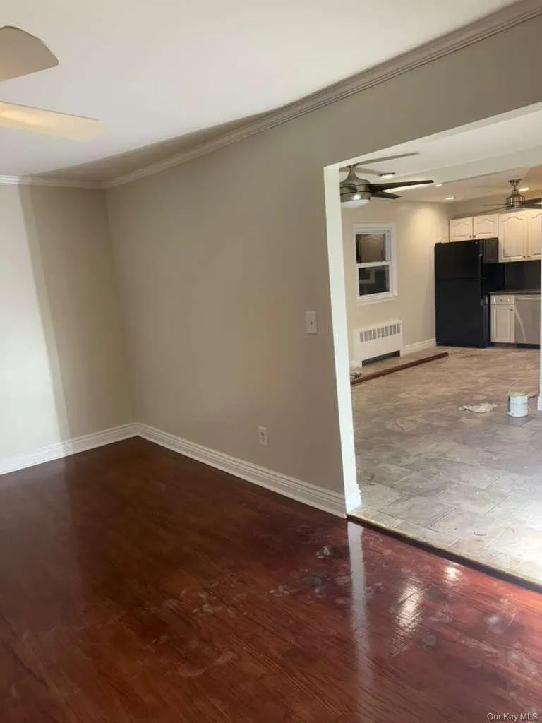 Spare room with ceiling fan, ornamental molding, dark wood finished floors, and radiator Spare room with ceiling fan, ornamental molding, dark wood finished floors, and radiator