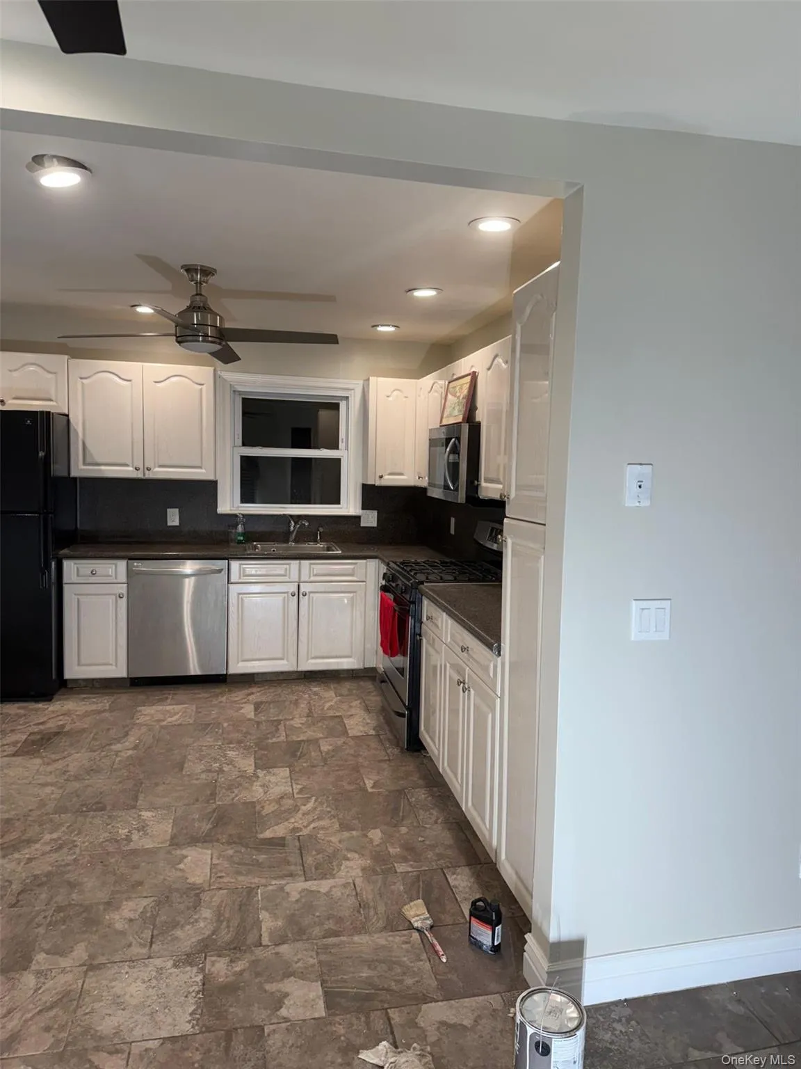 Kitchen with appliances with stainless steel finishes, stone finish floors, white cabinets, decorative backsplash, and recessed lighting Kitchen with appliances with stainless steel finishes, stone finish floors, white cabinets, decorative backsplash, and recessed lighting