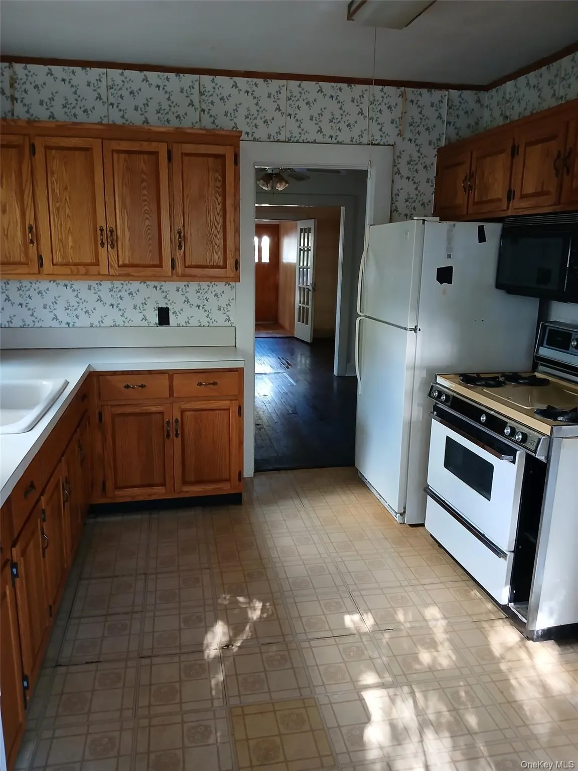 Kitchen featuring brown cabinetry, white gas range oven, light countertops, black microwave, and crown molding Kitchen featuring brown cabinetry, white gas range oven, light countertops, black microwave, and crown molding