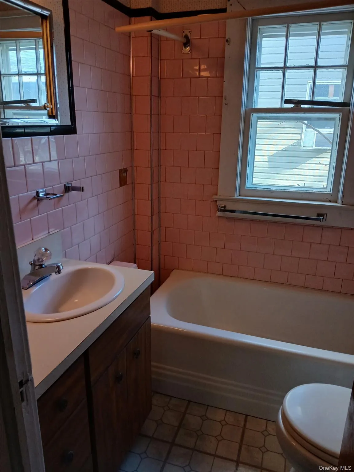 Full bath featuring healthy amount of natural light, vanity, tile walls, bathing tub / shower combination, and dark tile patterned floors Full bath featuring healthy amount of natural light, vanity, tile walls, bathing tub / shower combination, and dark tile patterned floors