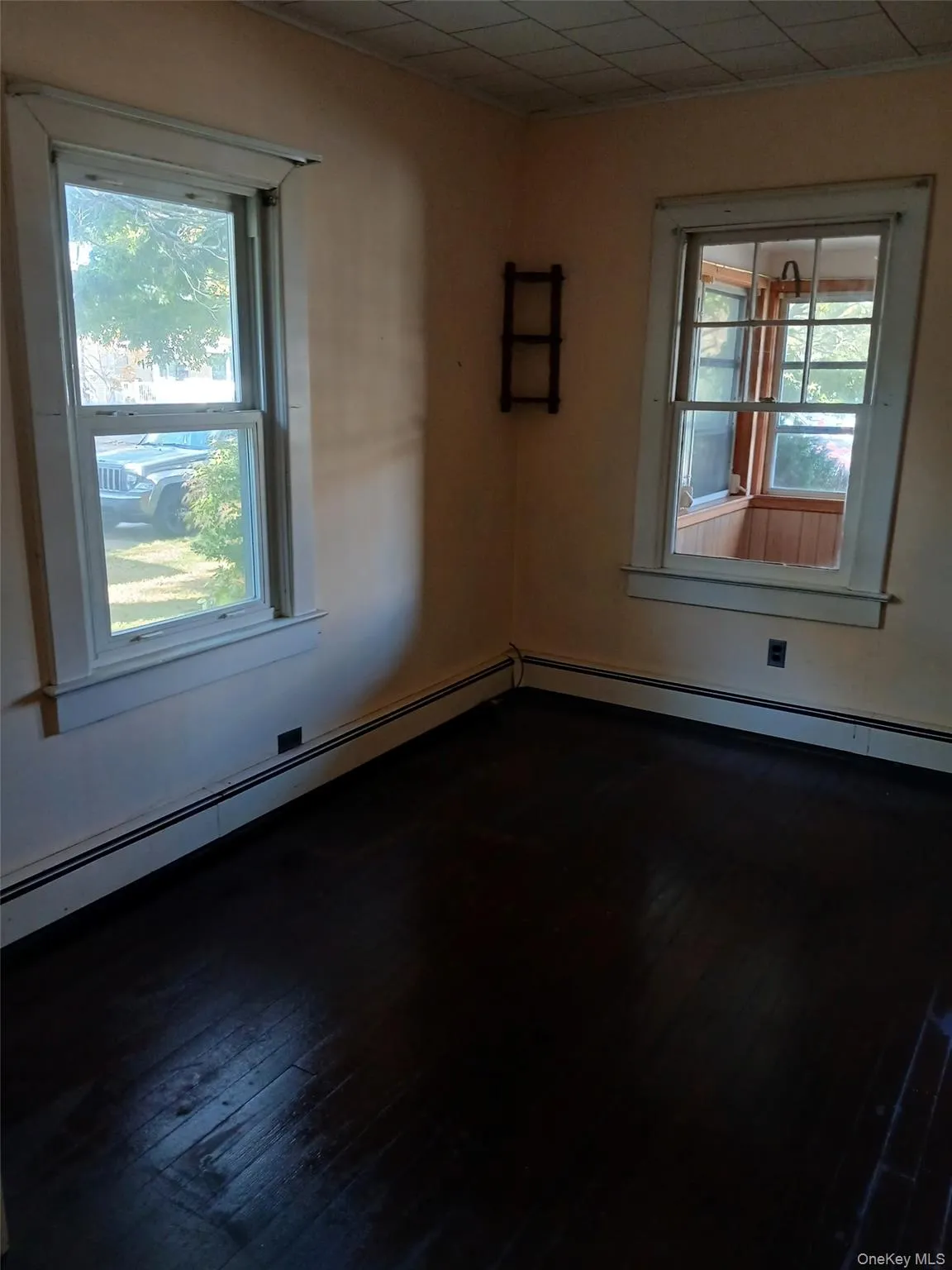 Unfurnished room featuring dark wood-style flooring and a baseboard heating unit Unfurnished room featuring dark wood-style flooring and a baseboard heating unit
