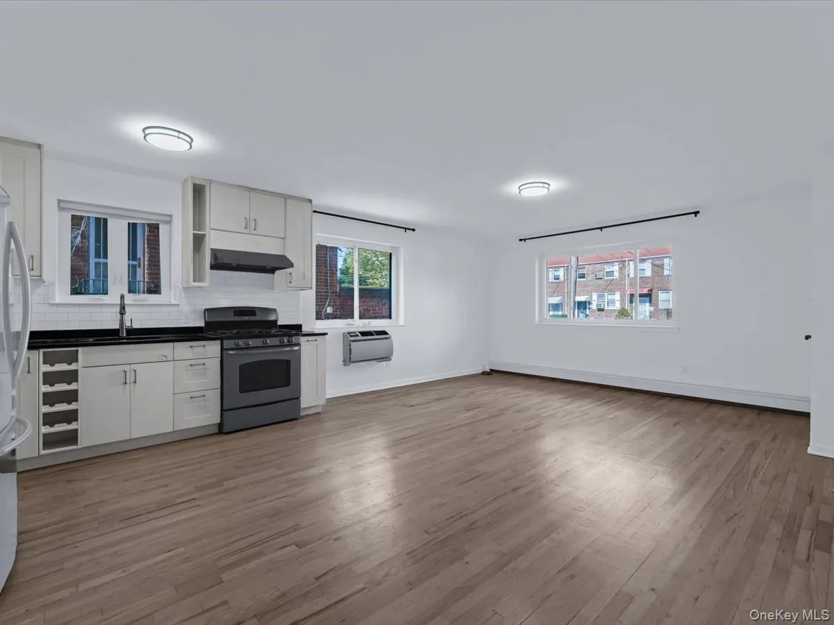 Kitchen featuring dark countertops, stainless steel appliances, light wood-style floors, decorative backsplash, and white cabinetry Kitchen featuring dark countertops, stainless steel appliances, light wood-style floors, decorative backsplash, and white cabinetry