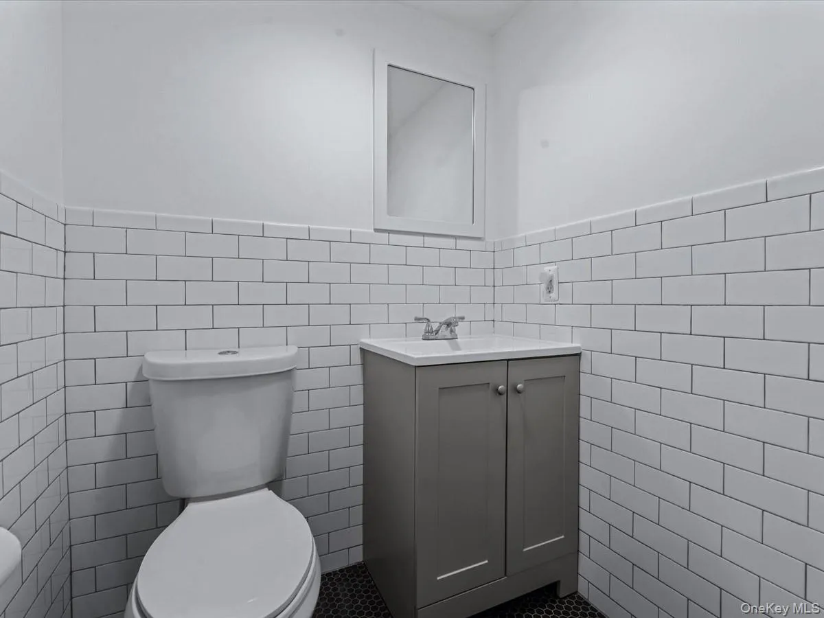 Bathroom featuring tile walls, vanity, and wainscoting Bathroom featuring tile walls, vanity, and wainscoting