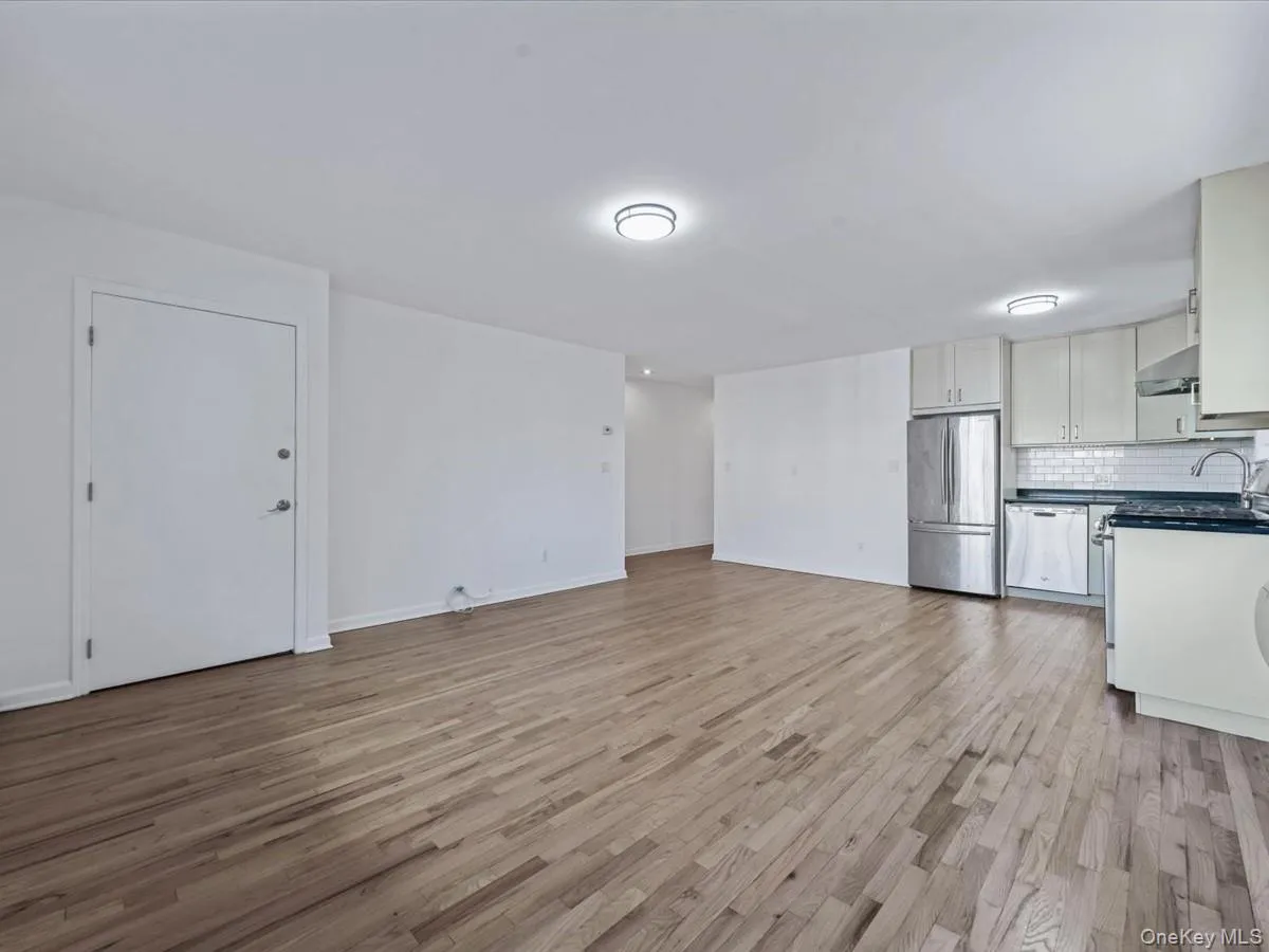 Unfurnished living room featuring light wood-type flooring and baseboards Unfurnished living room featuring light wood-type flooring and baseboards