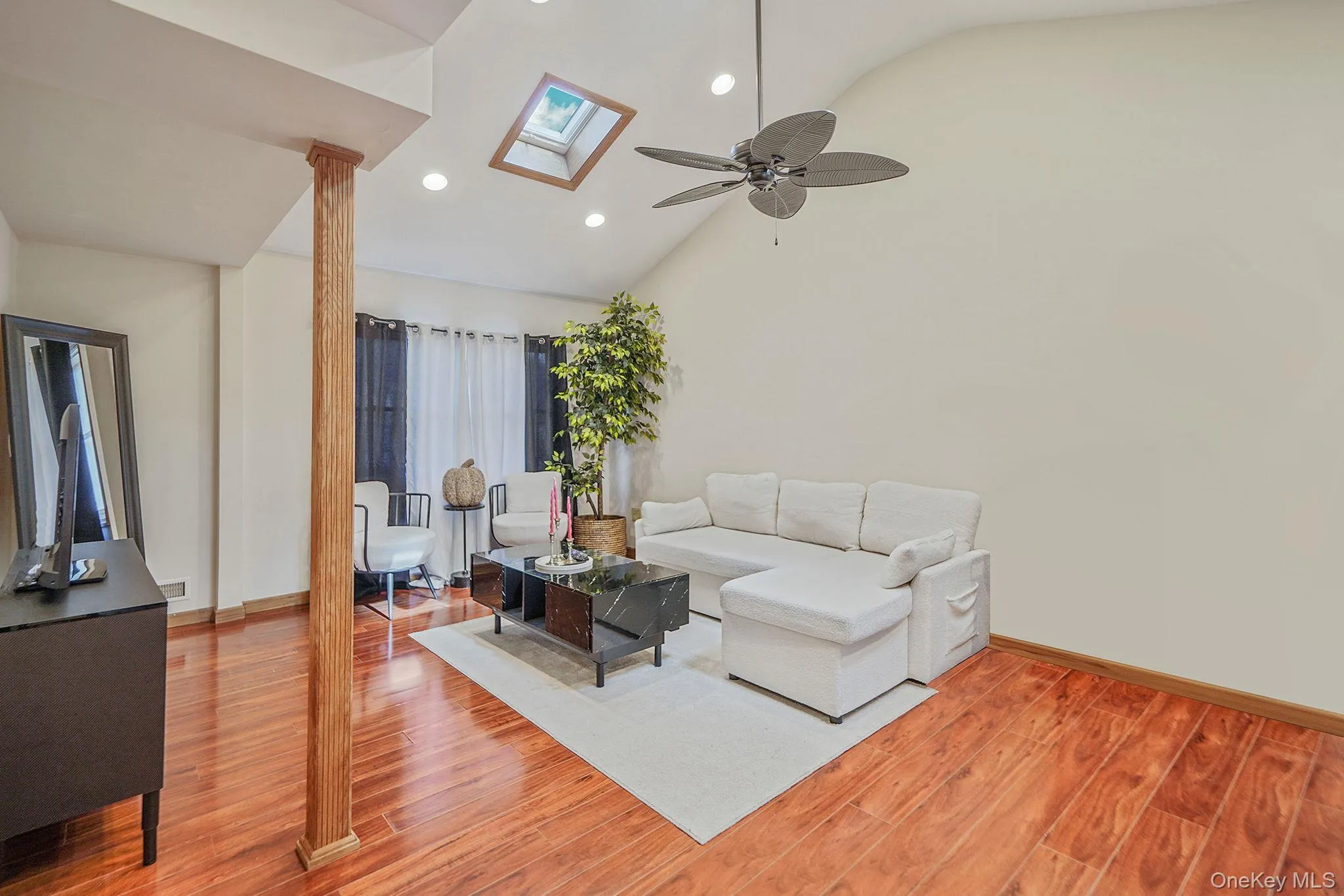 Living room featuring high vaulted ceiling, light wood-style floors, recessed lighting, a skylight, and a ceiling fan Living room featuring high vaulted ceiling, light wood-style floors, recessed lighting, a skylight, and a ceiling fan
