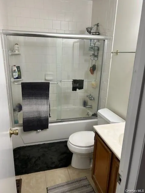 Full bathroom with enclosed tub / shower combo, vanity, and light tile patterned flooring Full bathroom with enclosed tub / shower combo, vanity, and light tile patterned flooring